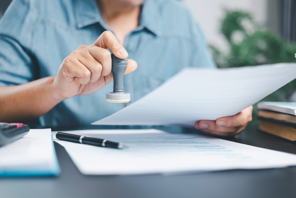 A person holding a pool building permit and stamping it with approval.