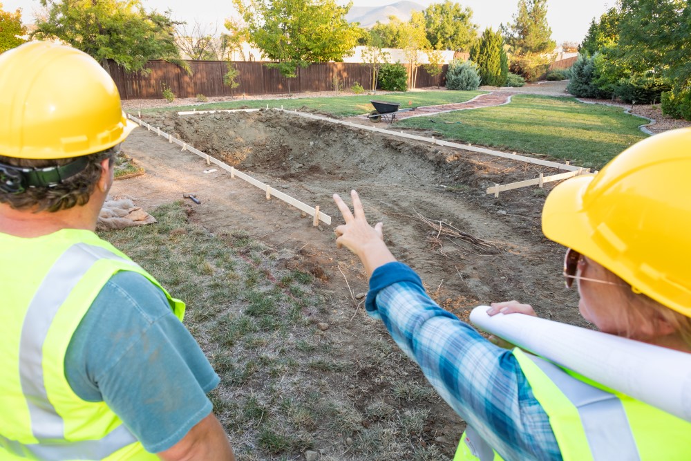 Two pool builders discussing the construction process of a new pool build.