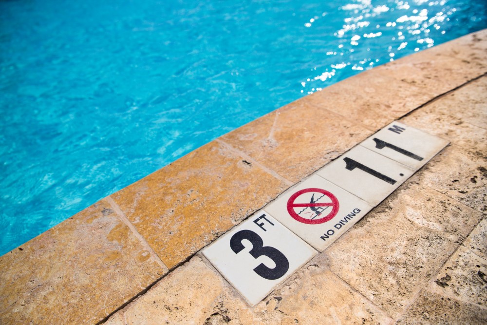 Signs outside of a pool signifying how deep the water is in that area of the pool.
